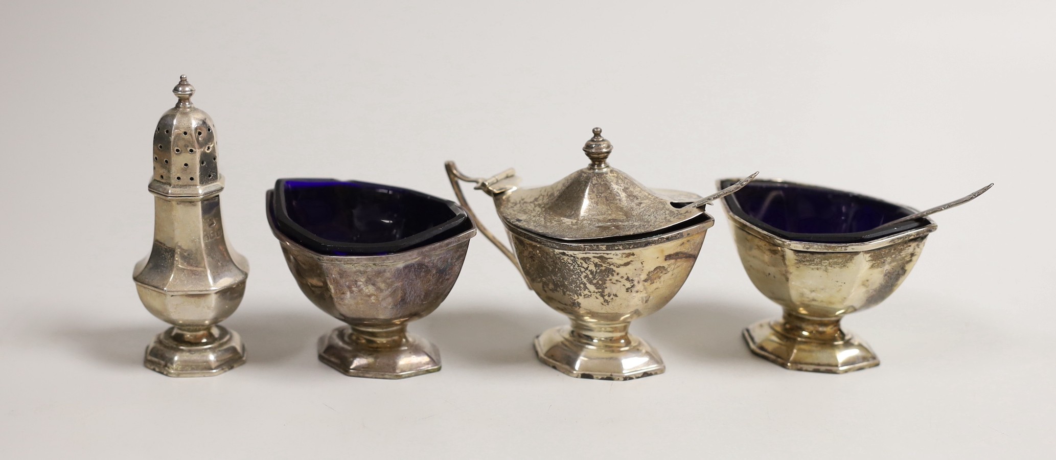 A George V silver four piece condiment set, by Adie Brothers, Birmingham, 1932 and two associated silver condiment spoons.